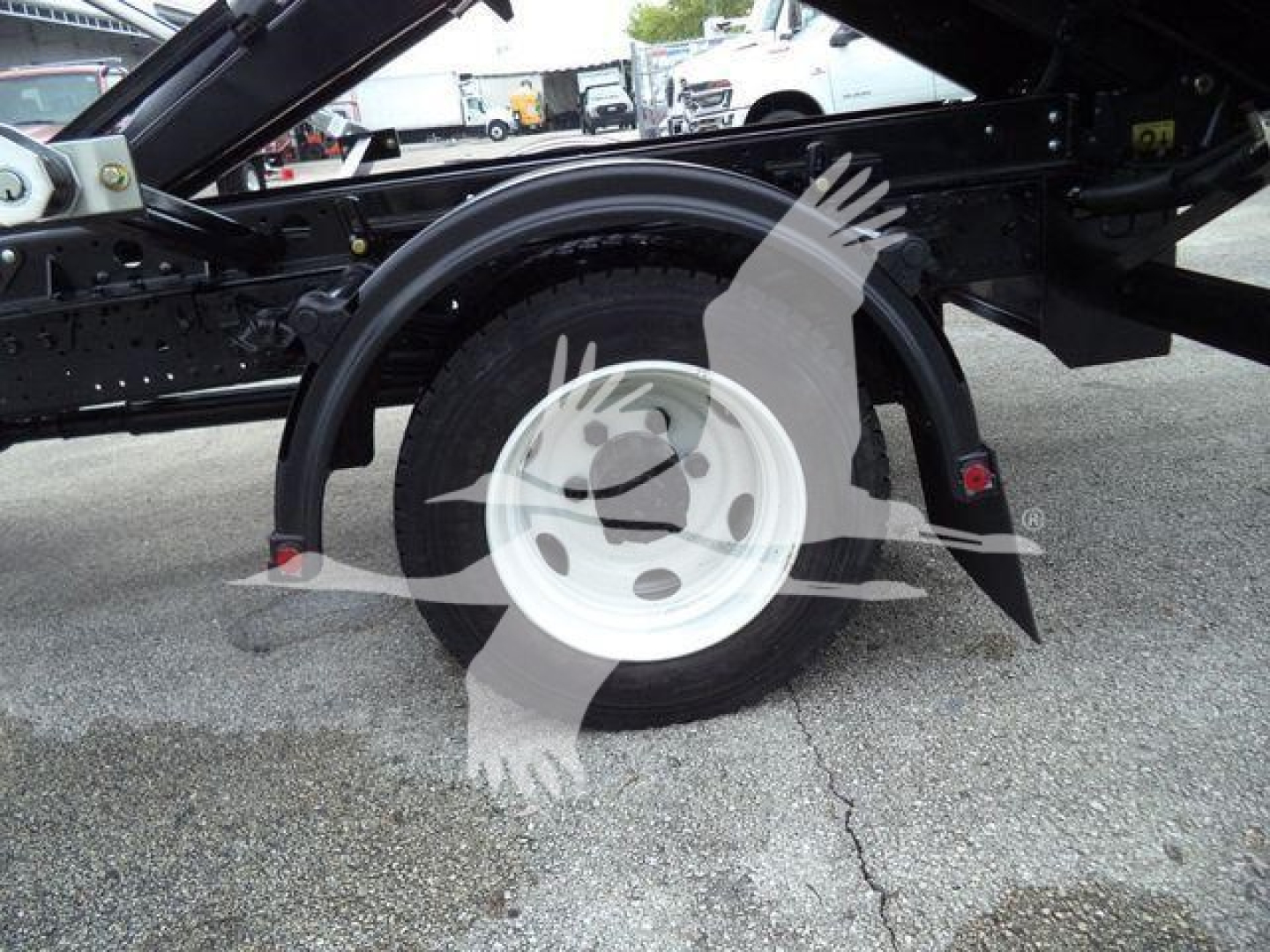 Truck wheel and suspension components of a 2019 Hino 195 roll-off truck showing a single rear wheel and fender with chassis framing.