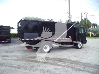 Side view of a 2019 Hino 195 roll-off truck with black body and gray graphics, cargo bed raised slightly, showing wheel, cab, and signage.