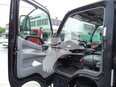 Cab interior of a 2019 Hino 195 roll-off truck with driver-side door open, showing steering wheel, dashboard, and grey interior trim.
