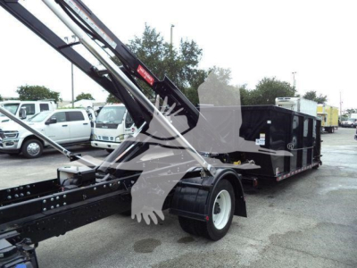 Hino 195 roll-off truck with long dump body and crane arm visible, front view of wheel and chassis.