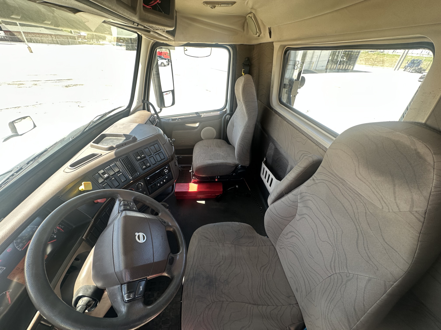 Cab interior of a 2018 Volvo VNL64T300 truck showing steering wheel, dashboard, driver seat, passenger seat, and side windows.