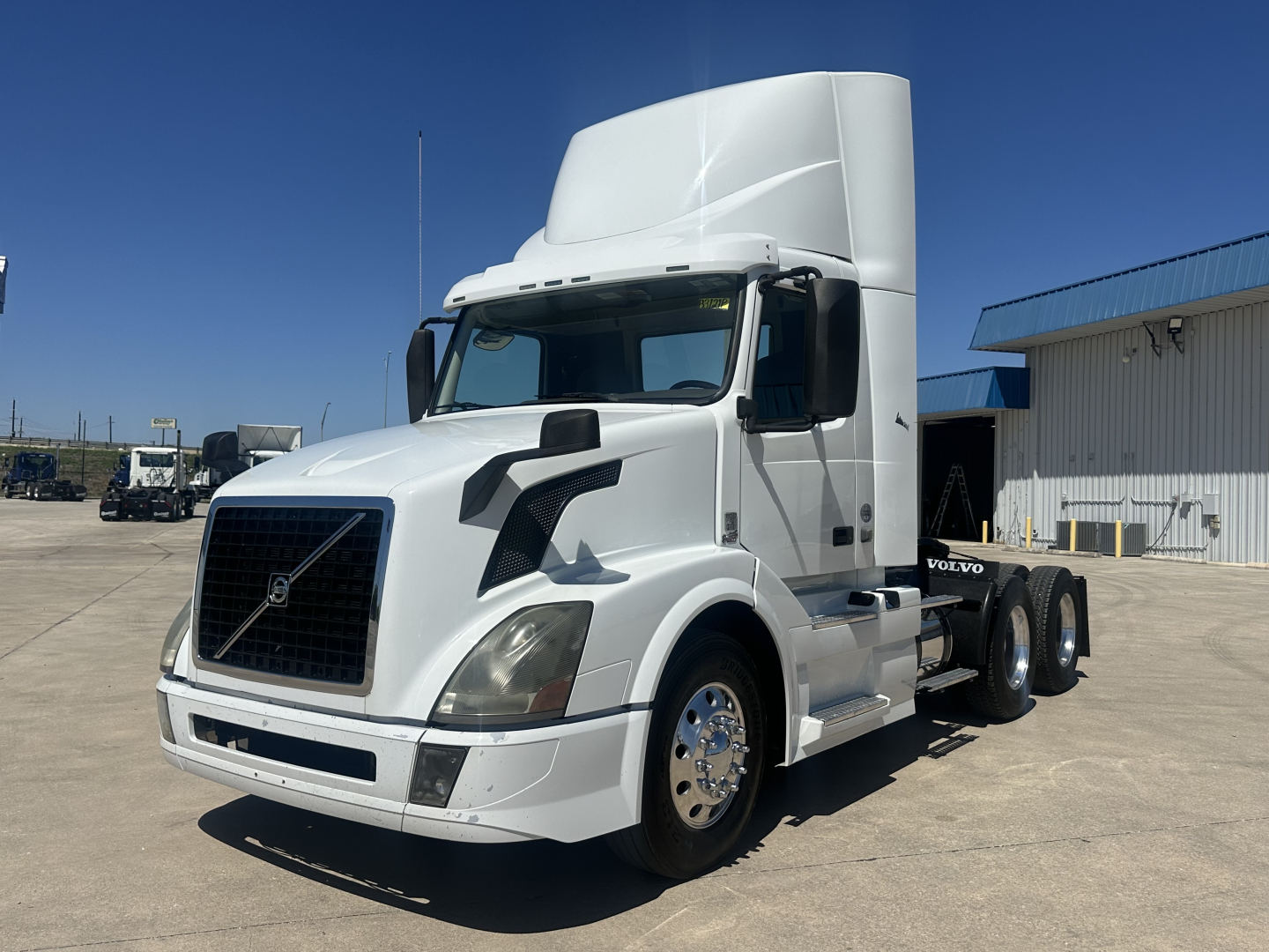 Volvo VNL64T300 conventional daycab tractor in white, front-left view, with tall sleeper fairing and dual rear axles.