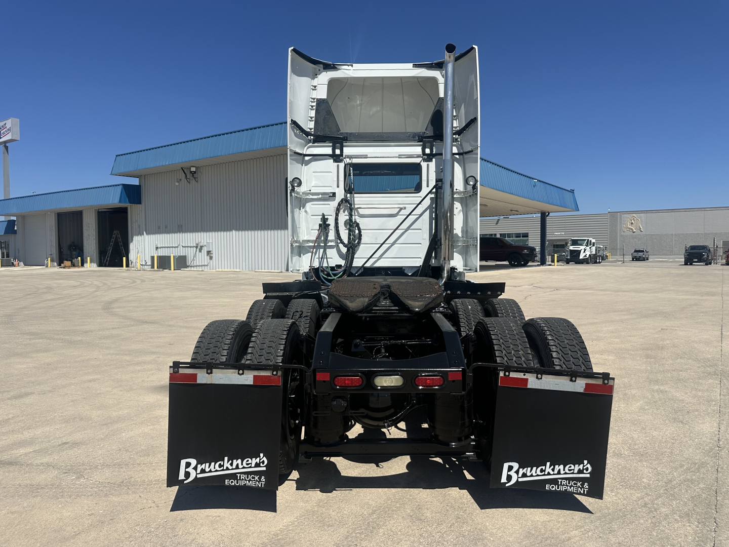 Volvo VNL64T300 tractor rear view showing fifth wheel, dual rear axles, mud flaps with Bruckner’s branding, and exhaust stack area.