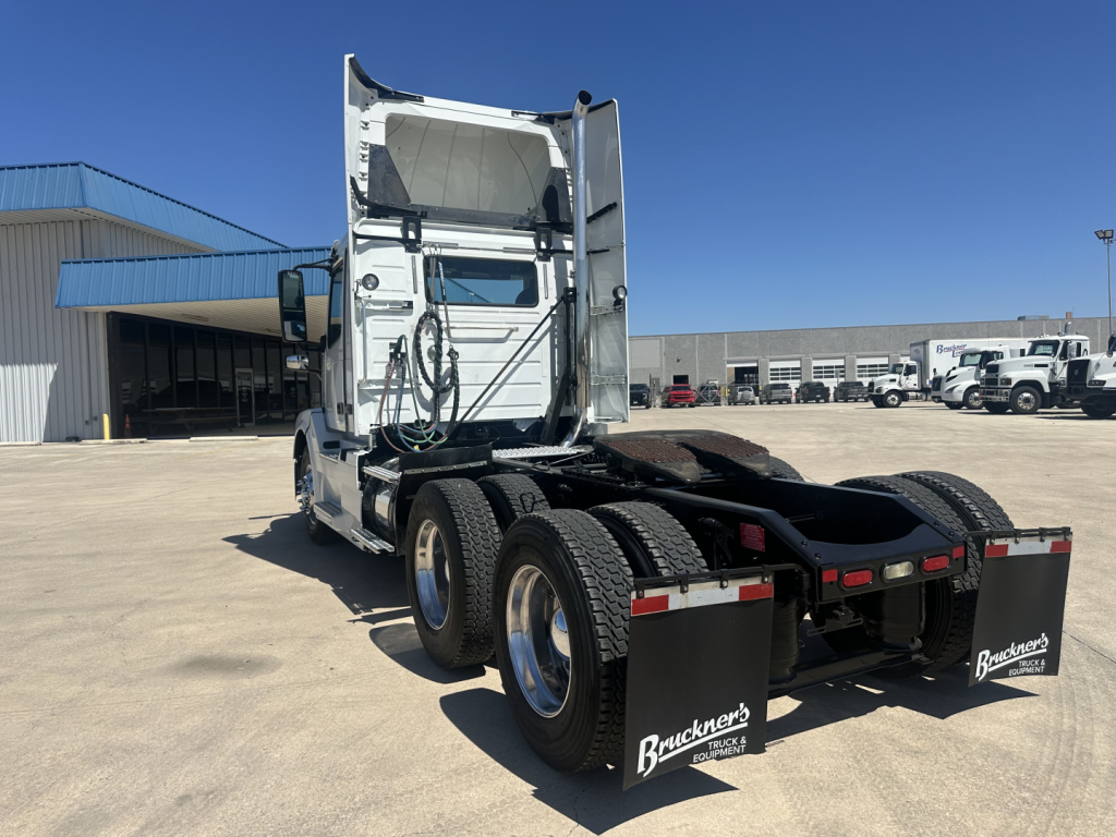 Volvo VNL64T300 tractor rear view showing tandem axles, fifth wheel missing, mud flaps with Bruckner’s logo, white cab, clear sky.