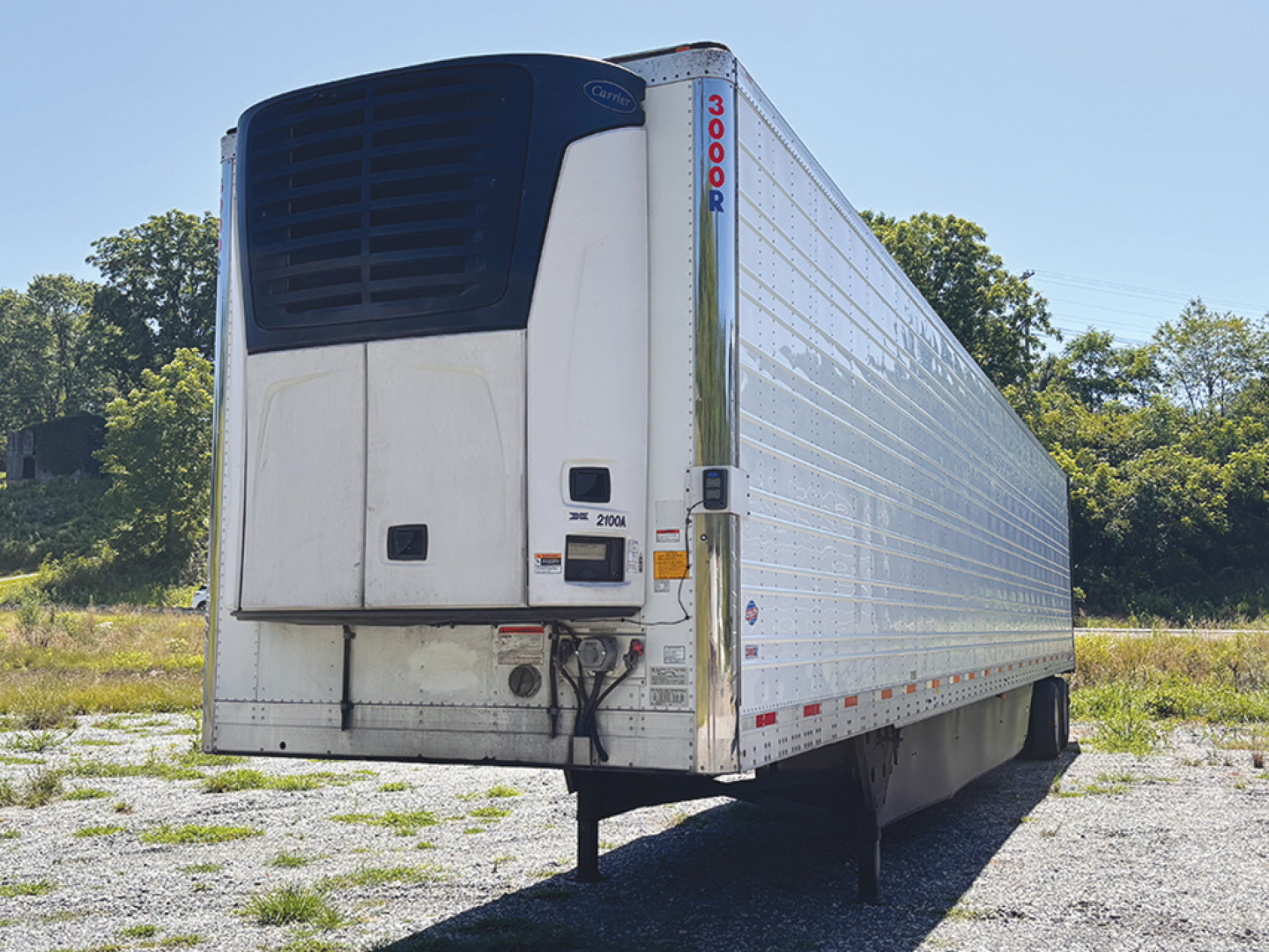 Utility 3000R trailer with rear refrigeration unit and vertical cooling fins, side view showing airfoil doors and reflective striping.