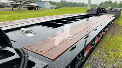Trailer deck of a Fontaine lowboy showing wooden planks and metal frame with hydraulic ramps in the background.