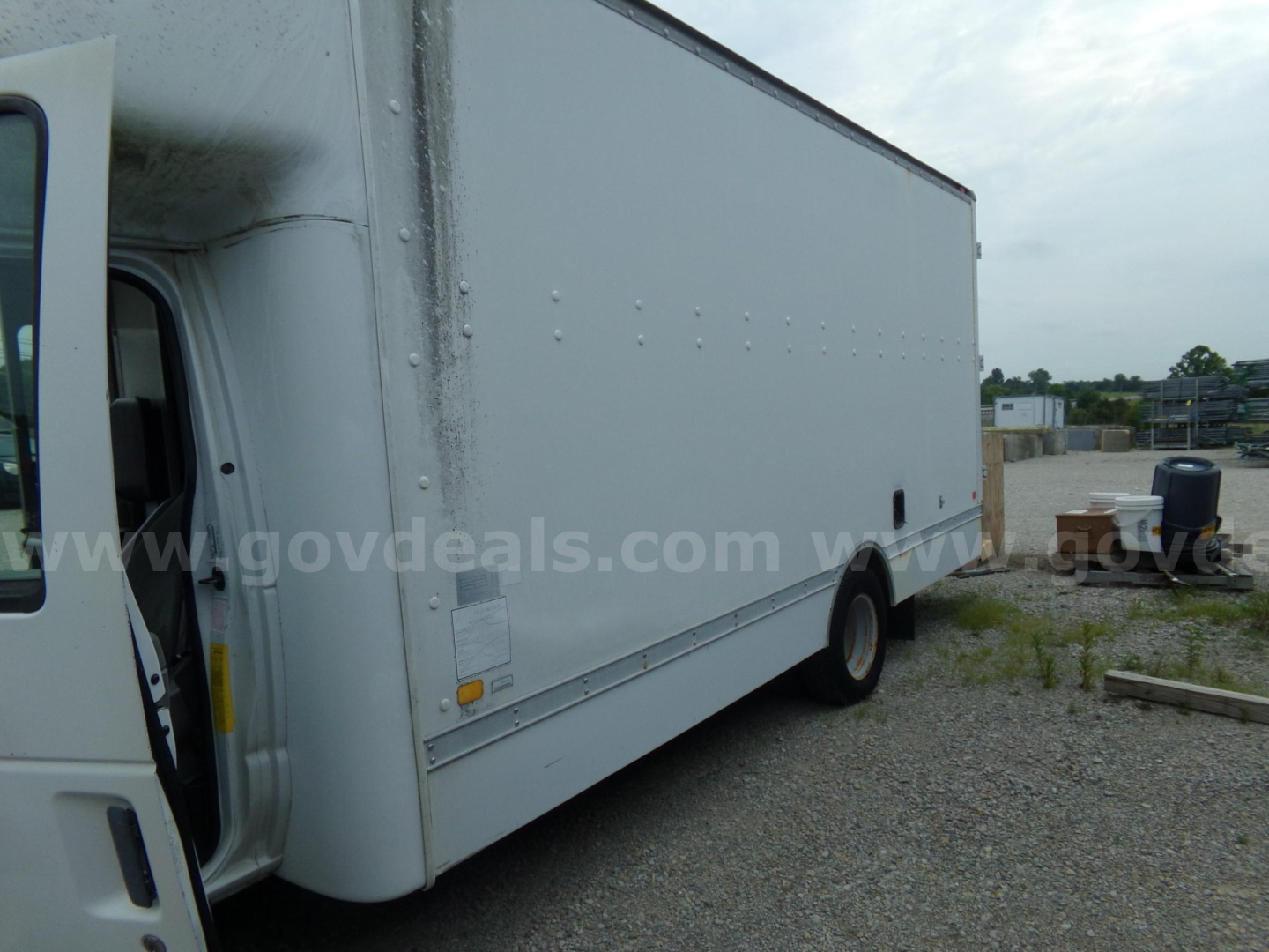 Box truck side view showing cargo box and cab of a 2003 Ford E456 with open door.