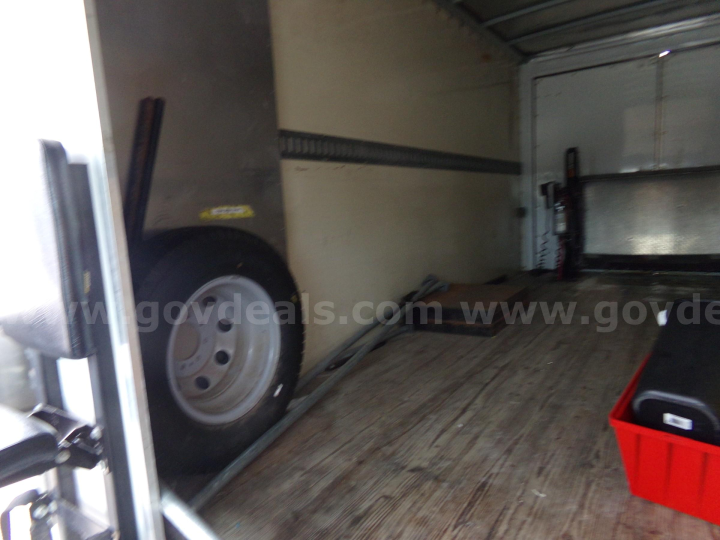 Truck interior cargo area with wheel and equipment rack visible.