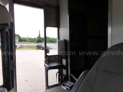 Truck cab interior showing doorway to cargo area and partial view of outside yard.