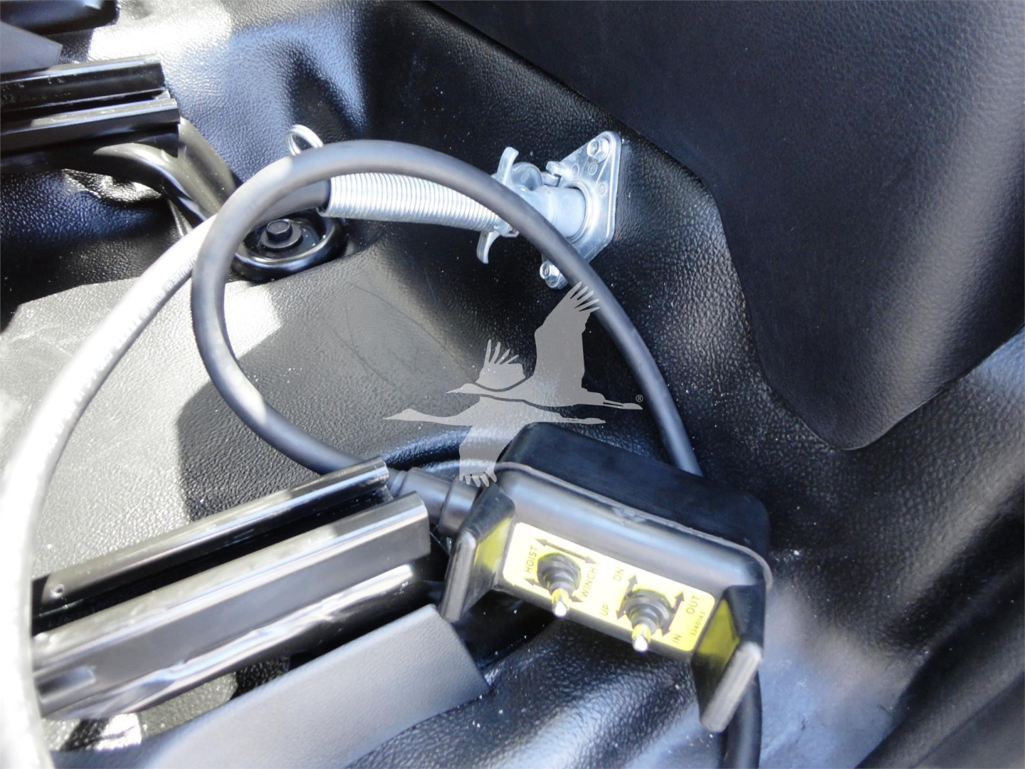 Cab interior showing a small control module with two screws and a looped cable, mounted under a black surface.