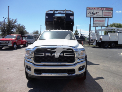 Ram 5500 heavy-duty truck front view with a hooklift system raised on the cab, GMC RAM logo grille, showroom lot in background