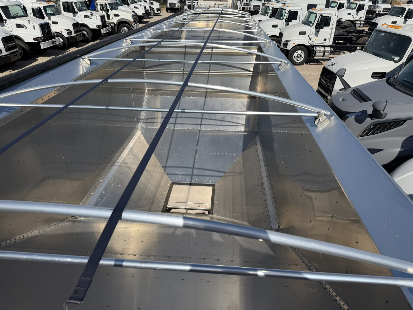Aluminum grain hopper trailer top view showing corrugated sidewalls, frame bars, and reflective metal surface.