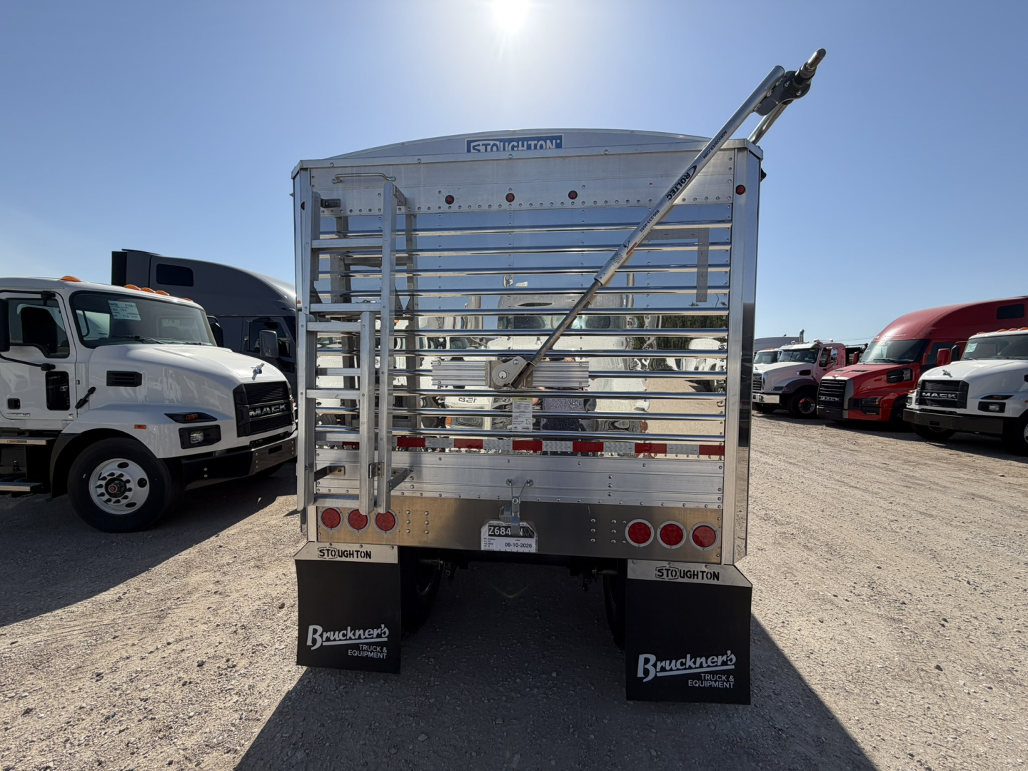 Stoughton 40' aluminum grain hopper trailer rear view with corrugated sidewalls and a rear ramp, chrome finish, multiple taillights, mud flaps, and VIN visible.