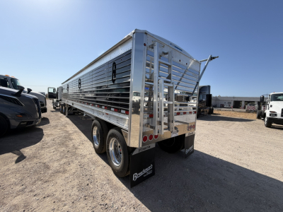 Trailer side view showing an aluminum grain hopper with 68" corrugated sidewalls, dual tires, rear gate, and mud flaps with Bucker Trucks branding.
