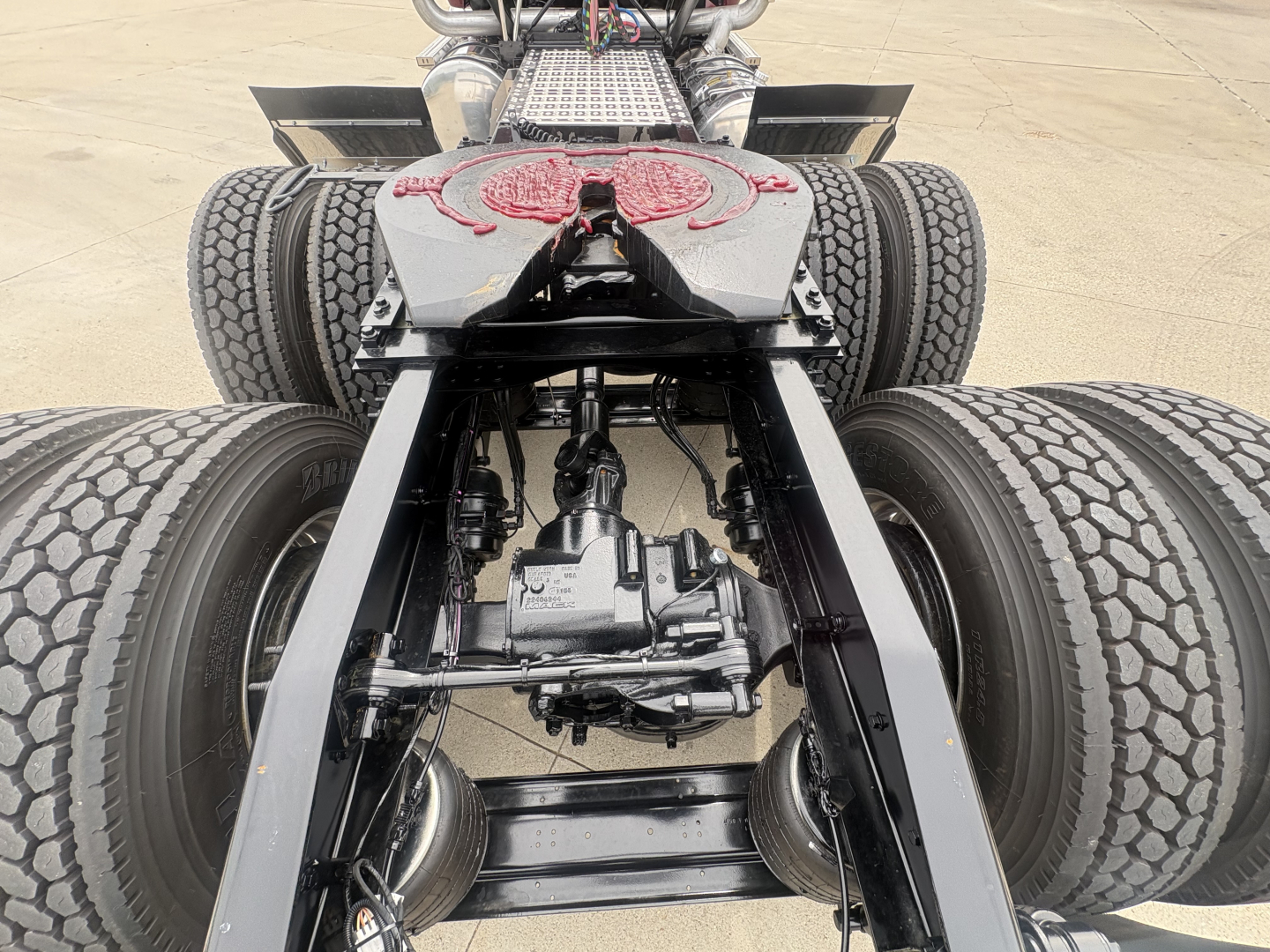 Mack PI64T chassis view showing drivetrain and dual rear axles with differential, undercarriage components and suspension in focus.