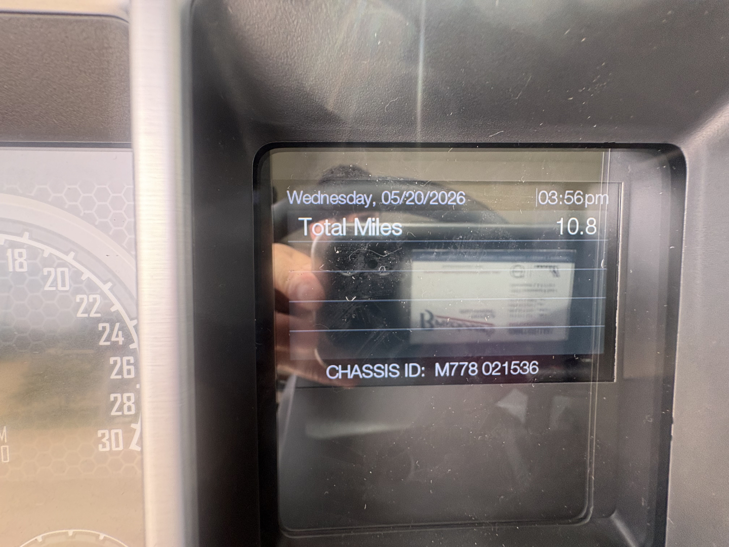 Truck cabin dashboard display showing date, total miles 10.8, chassis ID M778 021536, and partial instrument cluster