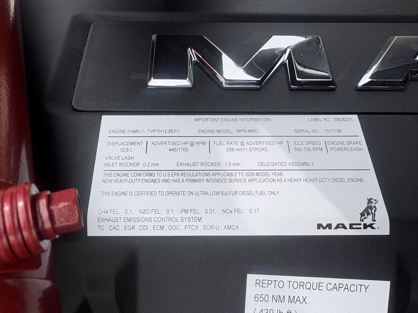 Engine data plate on Mack PI64T showing important engine information, including torque, emissions, and certifications. Brand MacK logo on right side.