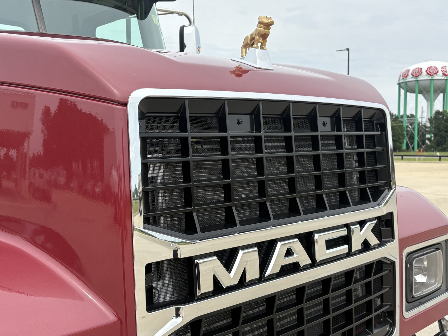 Mack PI64T truck front grille with bold MACk letters and chrome trim, red cab, DHL or brand badge on hood, close-up view