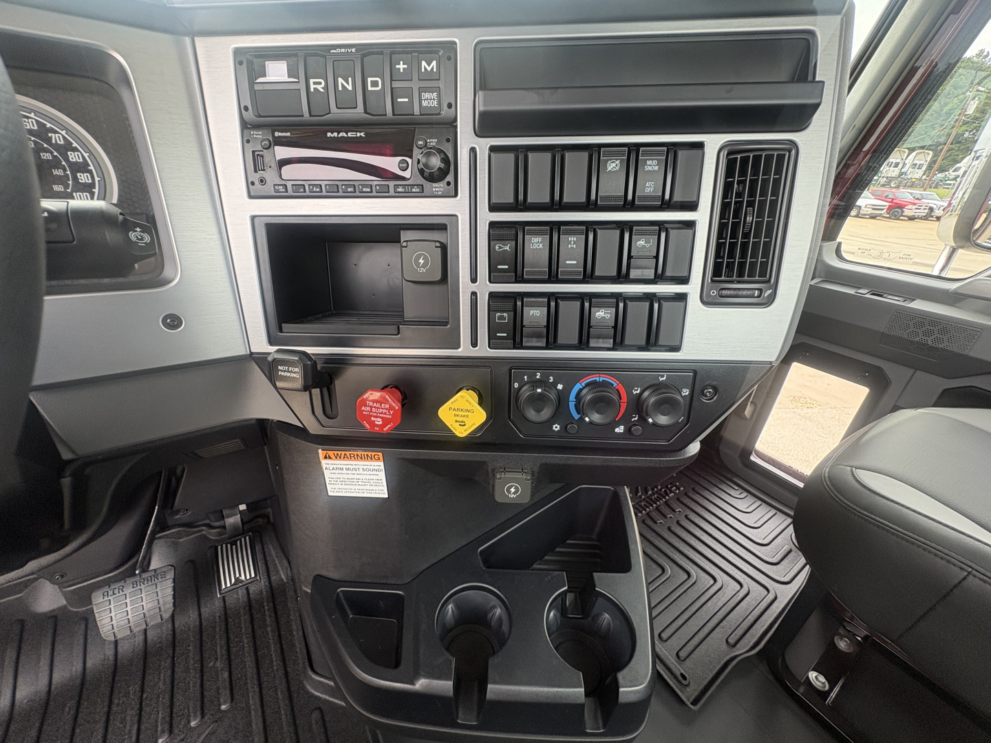 Mack PI64T truck interior dashboard view showing gear selector, climate controls, switches, and cup holders.