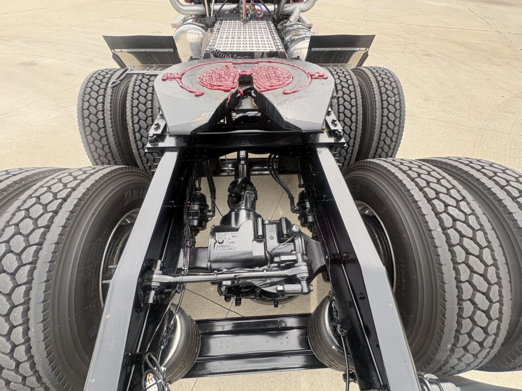 Mack PI64T chassis view showing drivetrain and dual rear axles with differential, undercarriage components and suspension in focus.