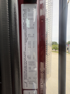 Vehicle door placard showing axle and gross weight ratings data for a Mack PI64T truck. Includes compliance and tire/wheel information and VIN-like label.