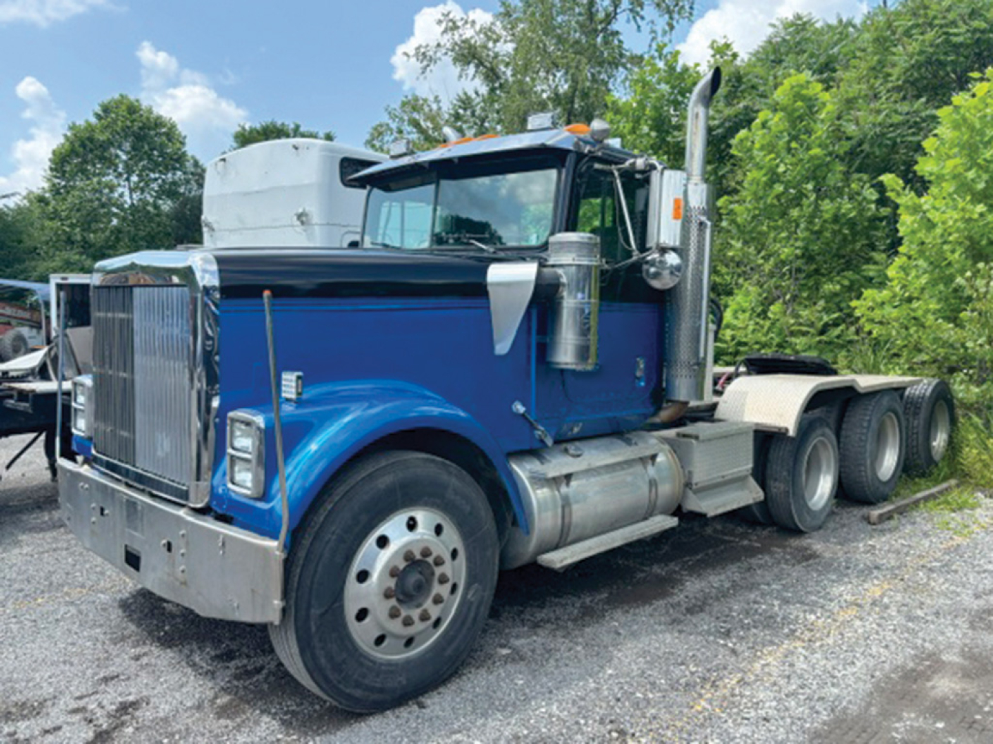 Front-left view of a blue 1998 International 9300 conventional daycab truck with dual rear axles and chrome exhaust stacks.