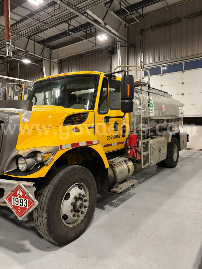2008 International 7400 water tanker truck in a warehouse with yellow cab and silver tank; front bumper, headlights, and warning placard visible; stock number plate and VIN text not legible.