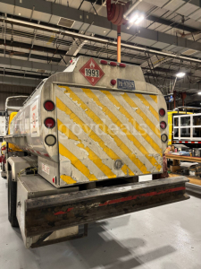 Back of tanker truck in warehouse showing hazardous material placard 1993 and 3, with yellow diagonal stripes and license plate BR-?0625, fuel/oil tank details.
