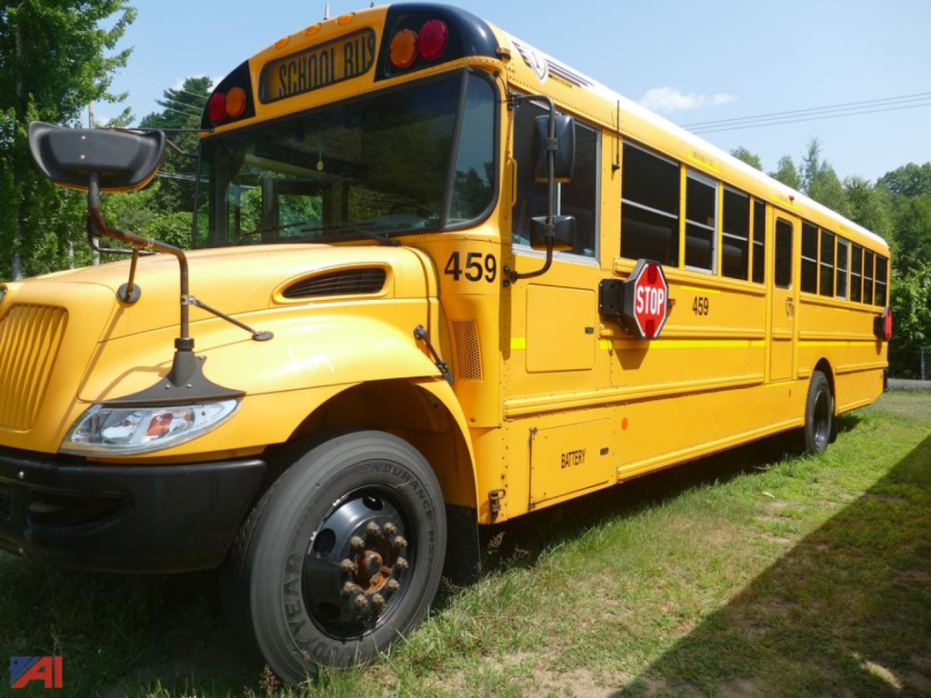 School bus labeled 459 with stop sign extended, front-left view, yellow International CE 3000 school bus, side doors open, parked on grass.