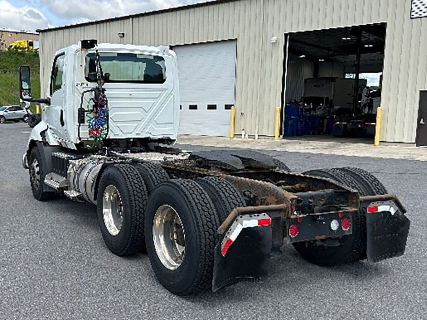 Tractor truck chassis of a 2019 International RH613 tractor showing rear dual-axle configuration with fifth wheel and exposed drivetrain in a dealership lot.