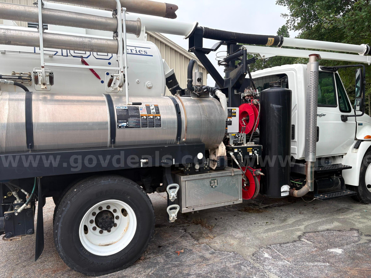 Truck side view showing large stainless tank and piping system on International 4300 vacuum truck with label details.