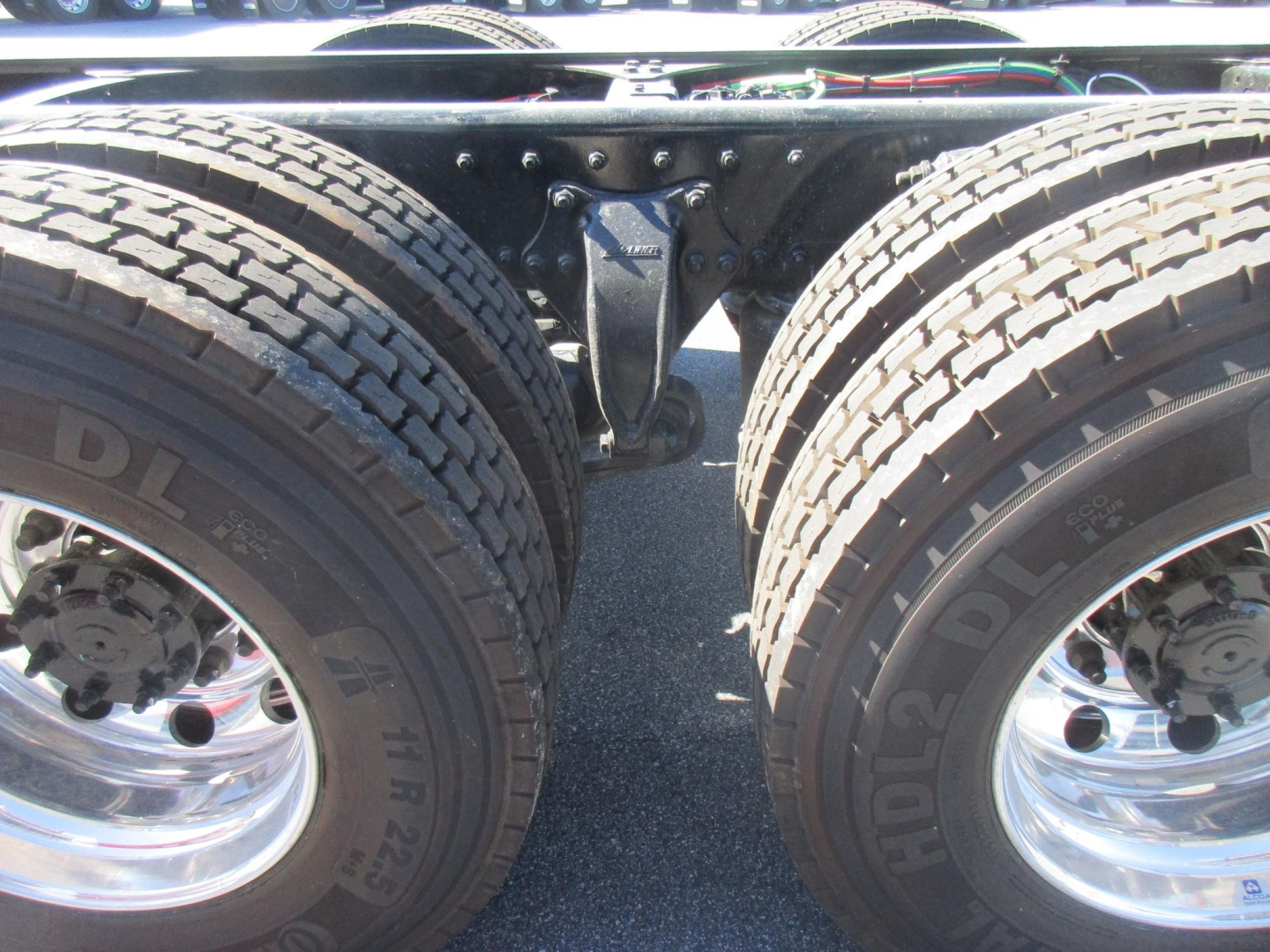 Truck chassis view showing dual rear wheels and suspension hanger with leaf springs and U-bolts.