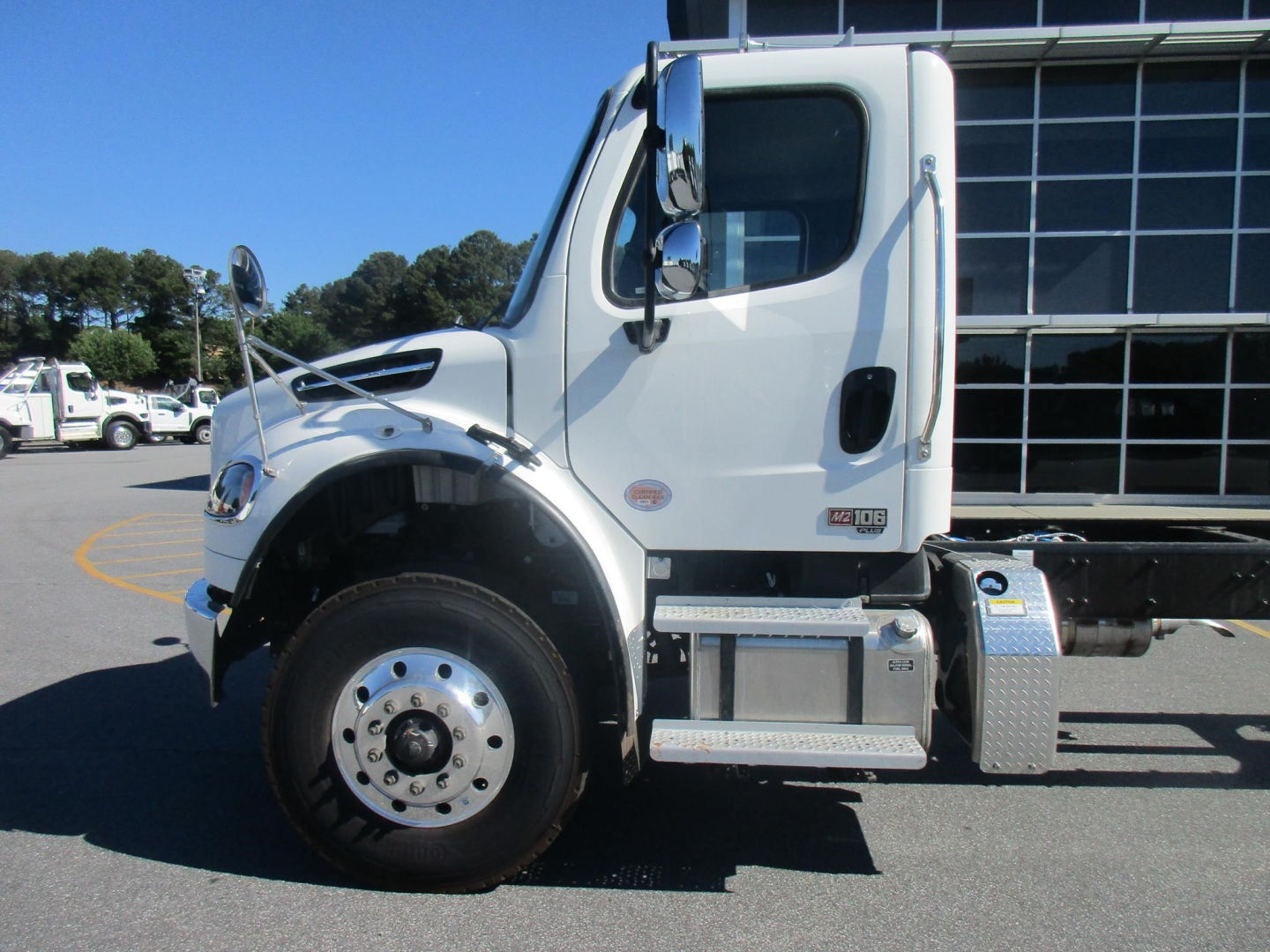 Freightliner Business Class M2 106 Plus cab chassis side view showing front wheel, chrome steps, and cab with window.