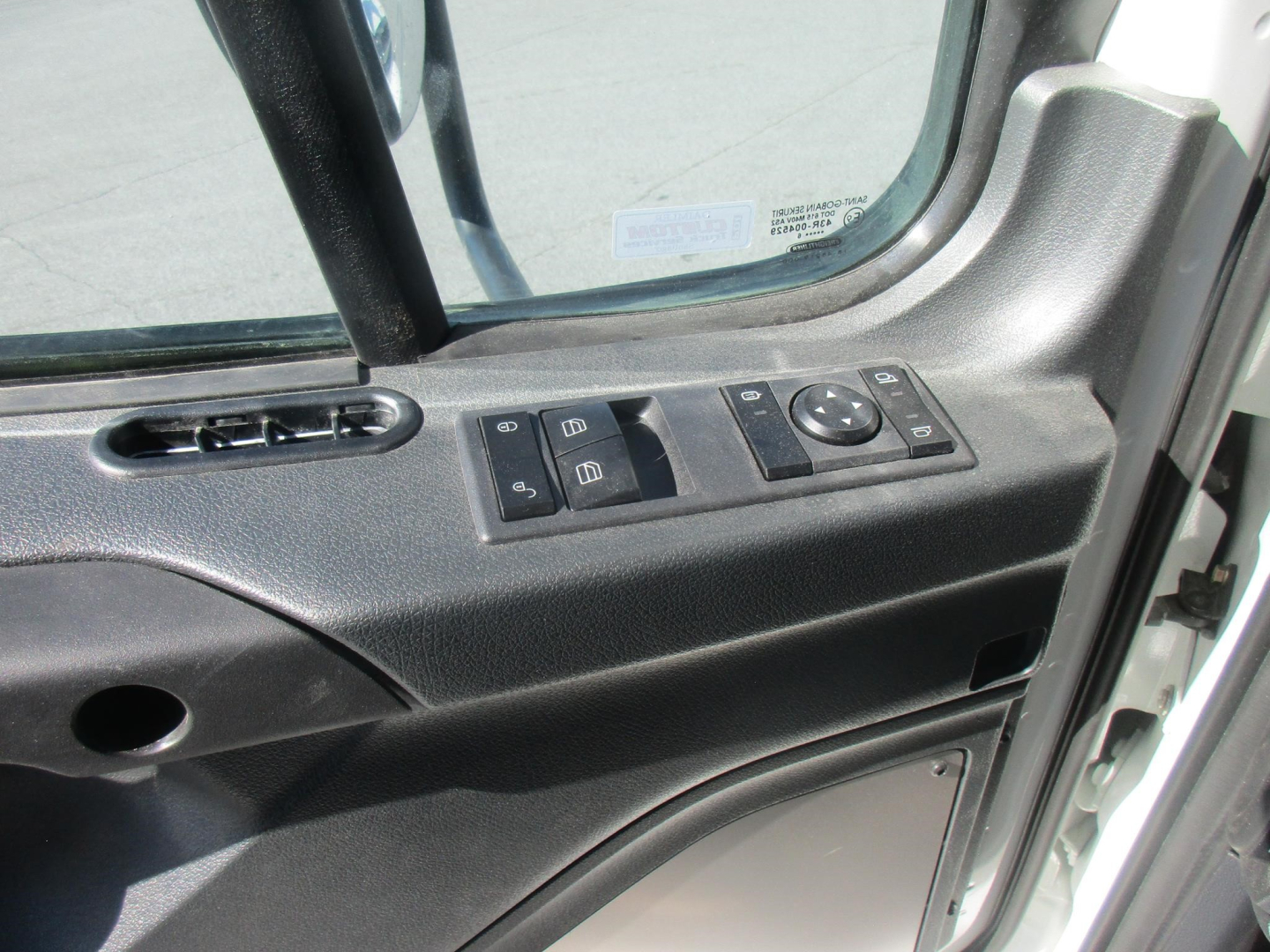 Cab interior door panel with window/lock controls in a Freightliner Business Class M2 106 Plus cab showing window switches and ventilation vent.