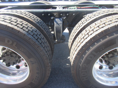 Truck chassis view showing dual rear wheels and suspension hanger with leaf springs and U-bolts.