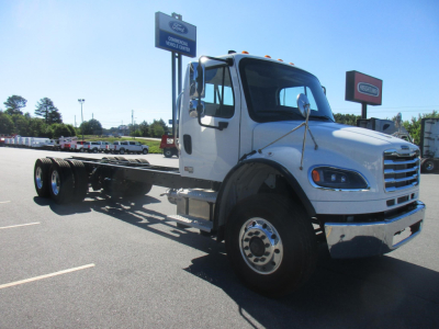 Truck image showing a white Freightliner Business Class M2 106 Plus cab and chassis with no body panels, front cab view, large windshield, rectangular headlights, and dual rear axles, external in-service components visible.