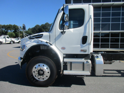 Freightliner Business Class M2 106 Plus cab chassis side view showing front wheel, chrome steps, and cab with window.