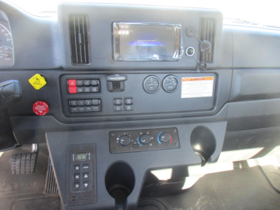 Dashboard and center console of a Freightliner Business Class M2 106 Plus truck showing radio/navigation screen, HVAC controls, switches, and cup holders.