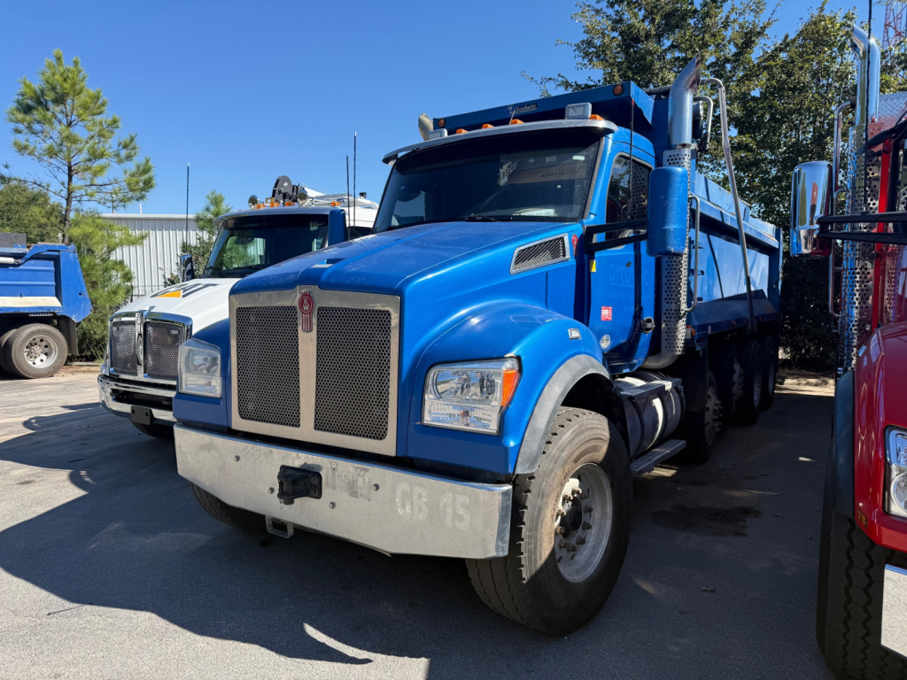 Blue 2019 Kenworth T880S dump truck in a dealership lot, front view showing grille, bumper, headlights, and side mirrors.