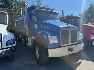 Blue 2019 Kenworth T880S dump truck front-left view with chrome grille, large bumper, and dual rear wheels visible.