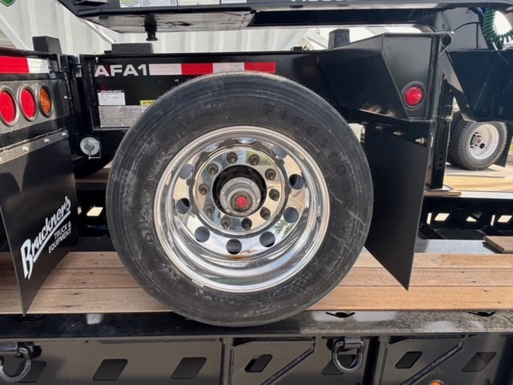 Trailer wheel assembly with chrome spoke wheel and black fender within a flip axle trailer, showing 'AFA1' label and wooden deck
