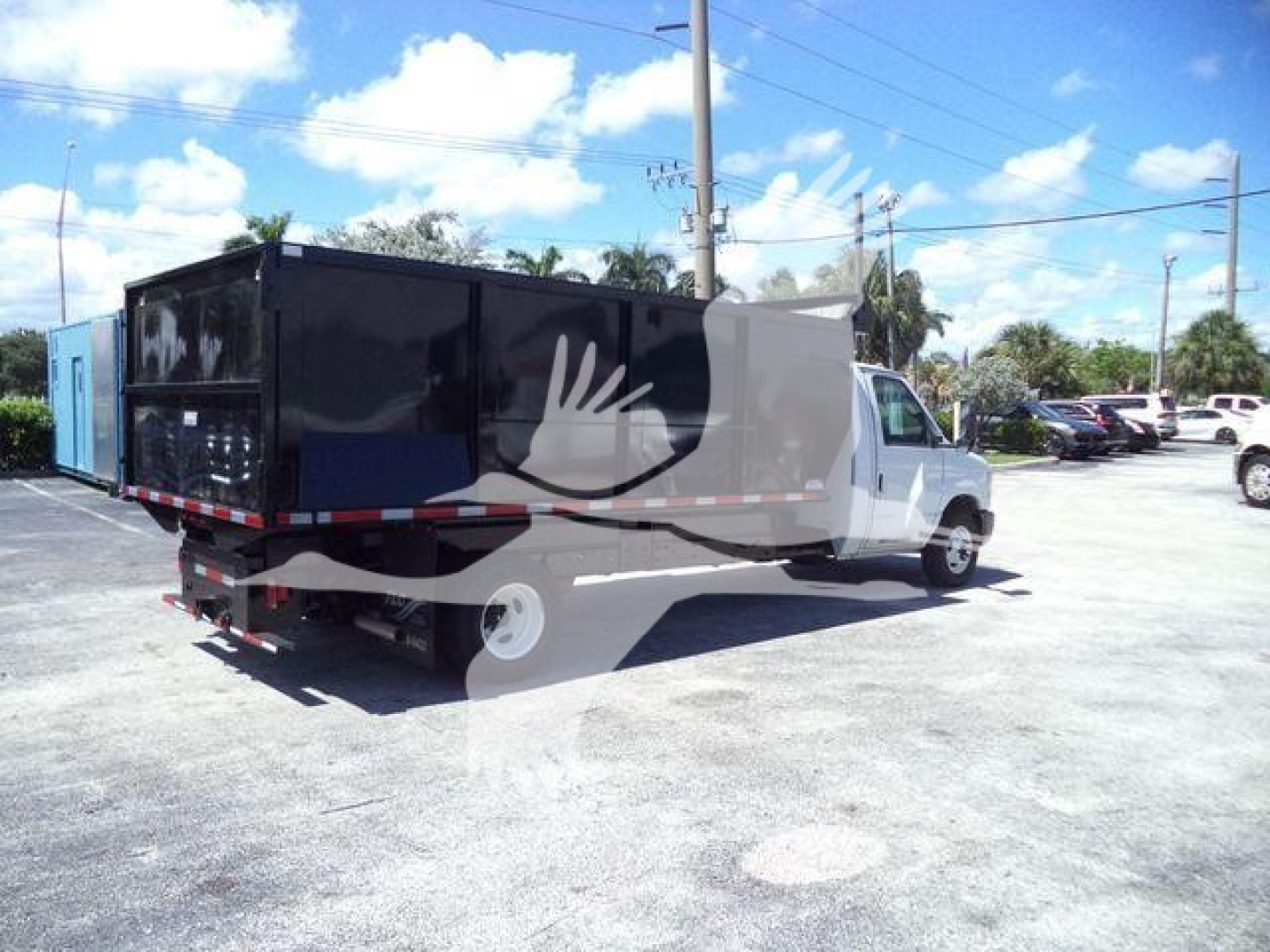 2011 Ford E450 dump truck with black dump body and blue equipment trailer attached, in a parking lot under blue sky.