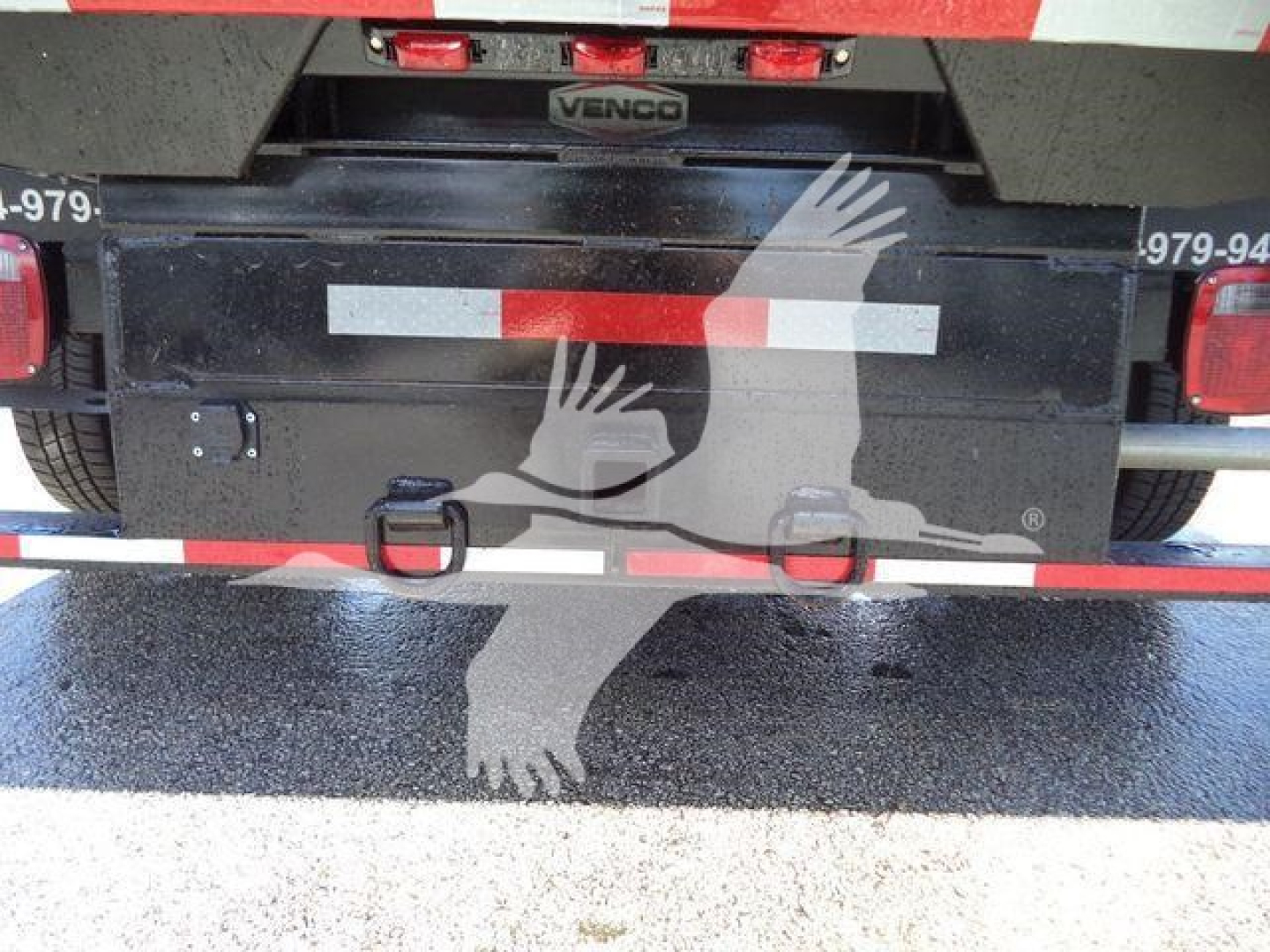 Rear of a 2011 Ford E450 dump truck showing tailgate with Venco badge and reflective red/white strips, bumper hooks, and license-like frame.