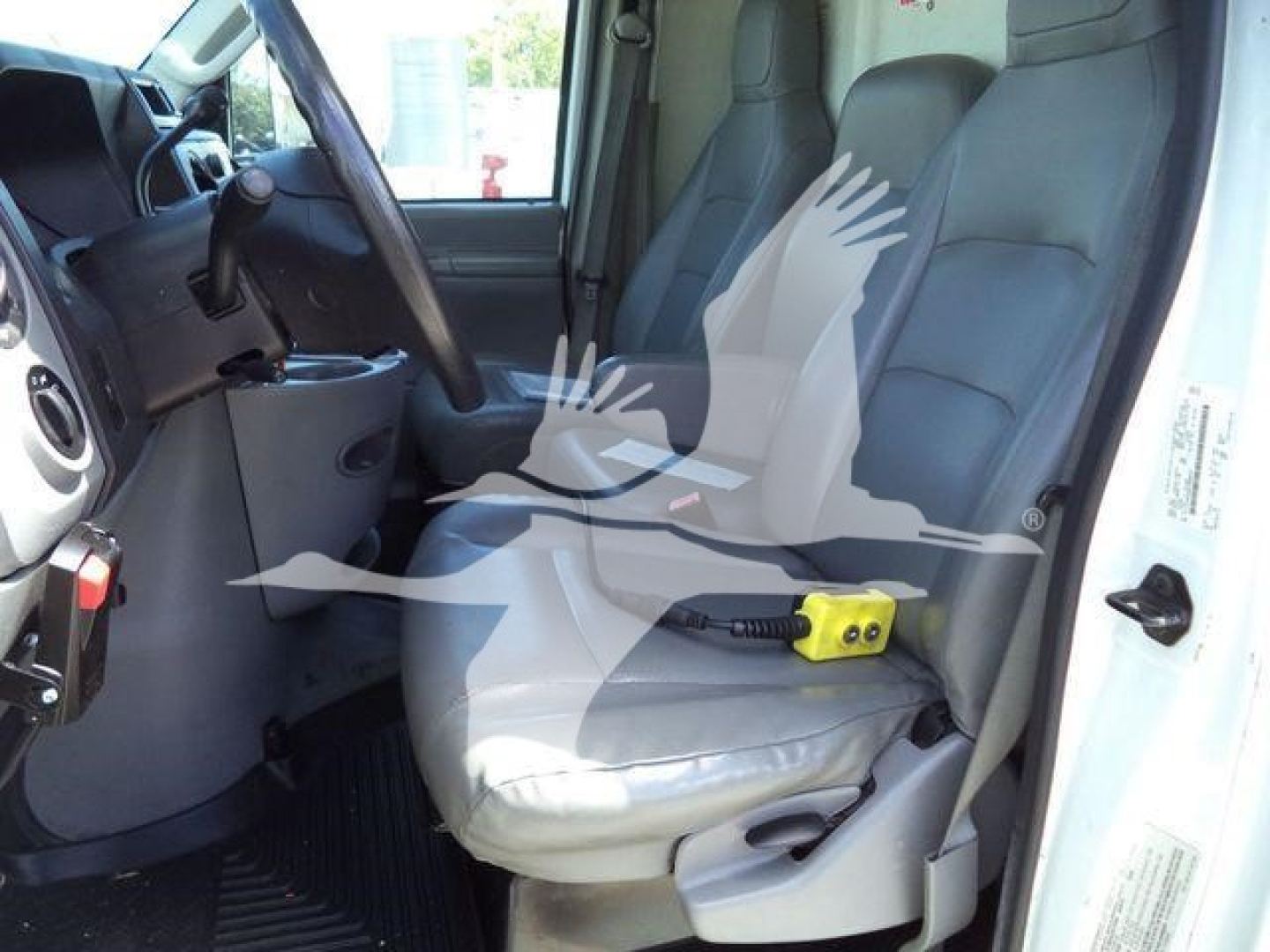 Ford E450 cab interior with front seats and dashboard; yellow portable device on driver's seat; steering wheel and controls visible.