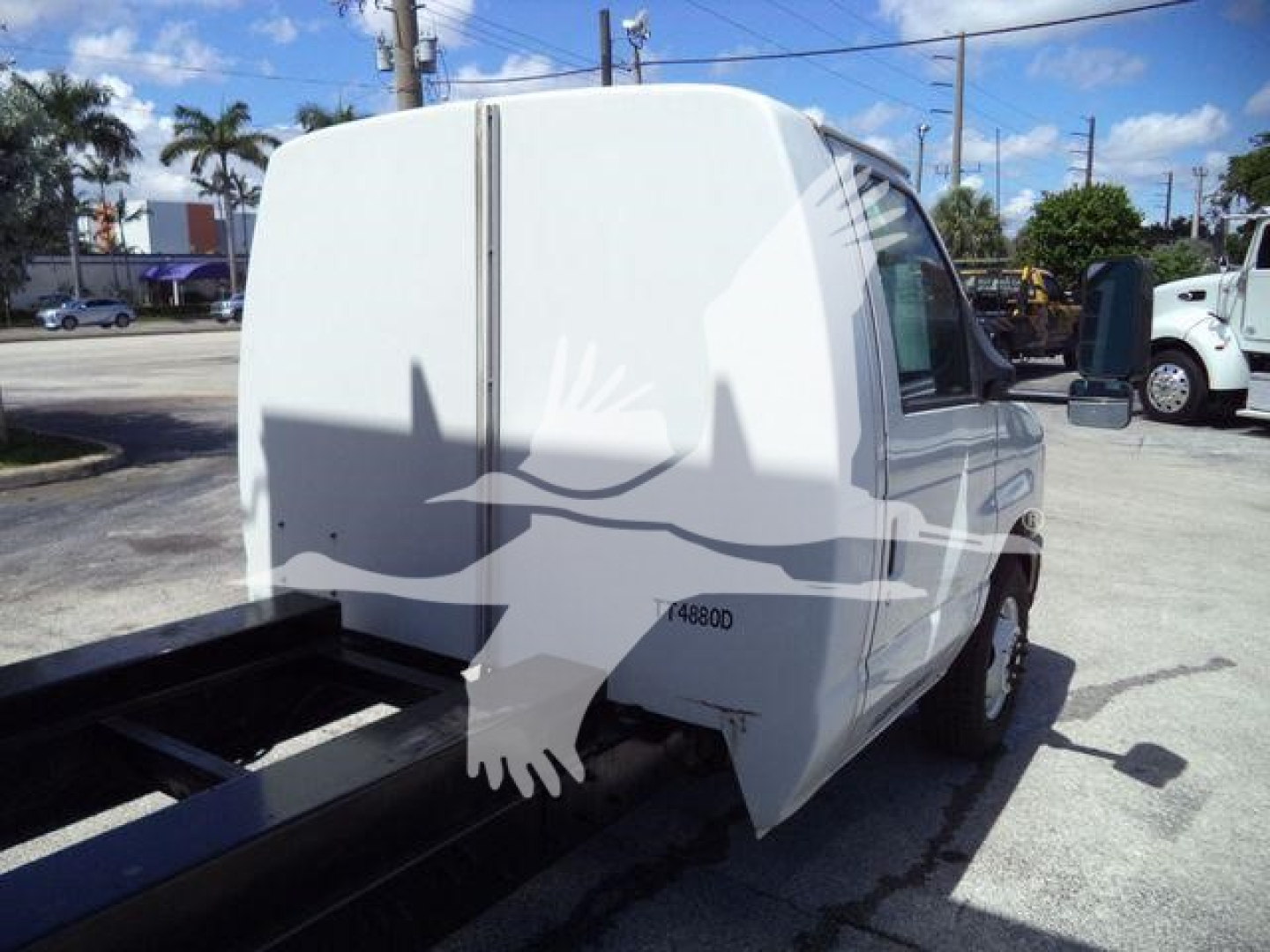 Ford E-Series cutaway cargo van body on a dump truck chassis rear view showing plain white cargo area and cab, side mirror, and wheel wells.