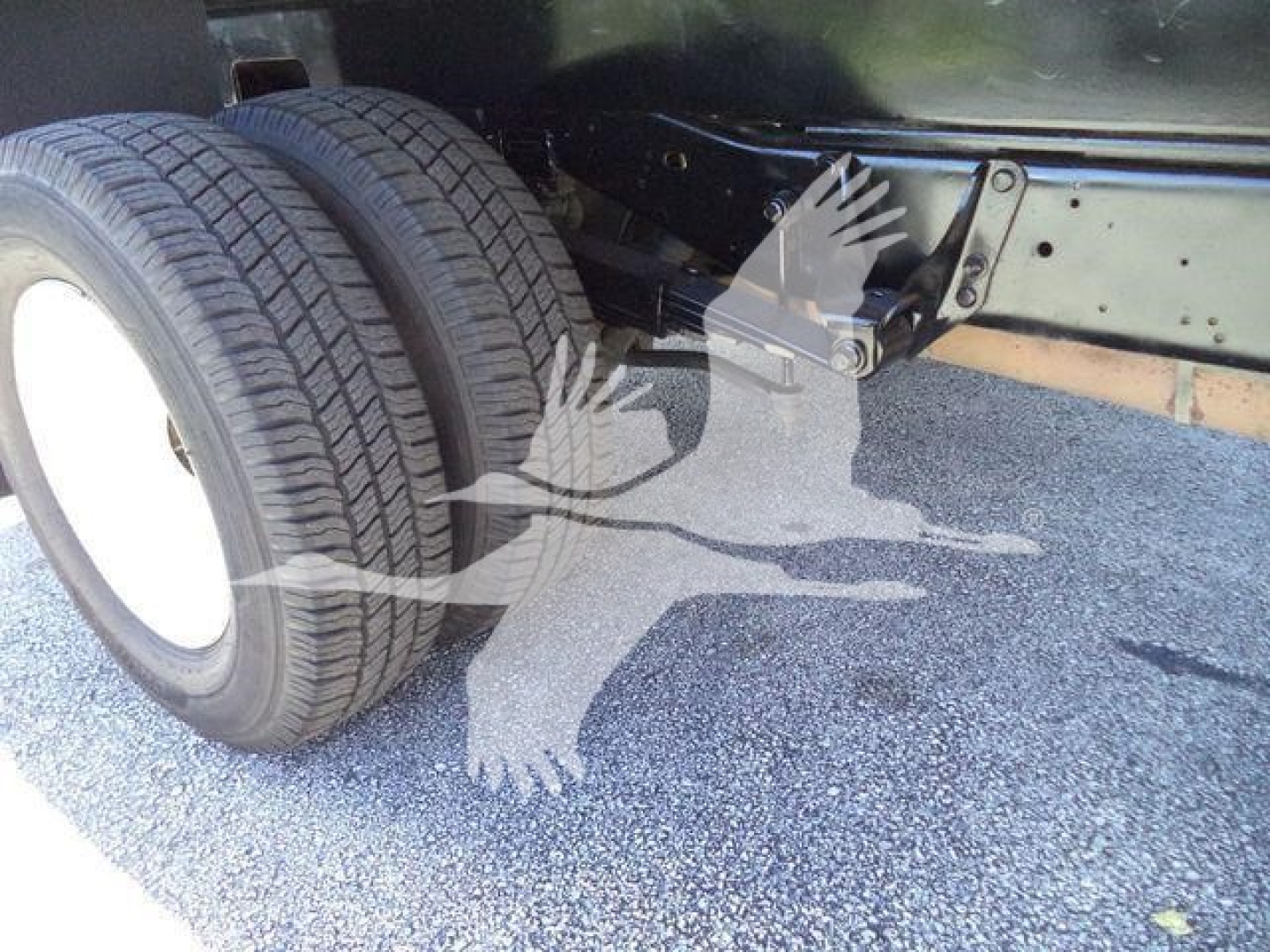 Ford E450 dump truck rear axle with dual tires and suspension components visible.