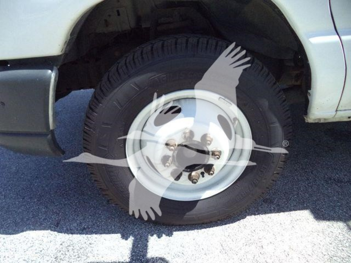 Ford E450 wheel and tire view with white steel rim and hub area