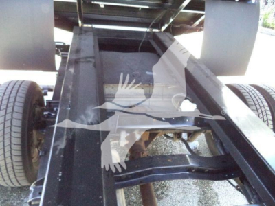 Chassis frame of a 2011 Ford E450 dump truck showing the long black steel frame rails and dual rear wheels.