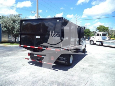 Black dump trailer attached to Ford E-450 chassis showing rear view with taillights and mud flaps.