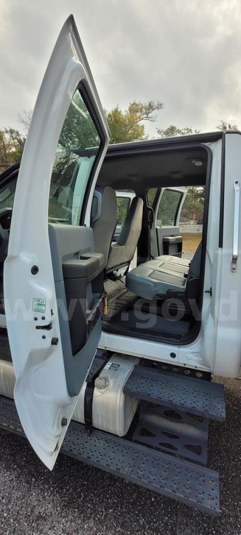 Ford F-650 cab step entry with open rear passenger door showing interior seating and box truck exterior.
